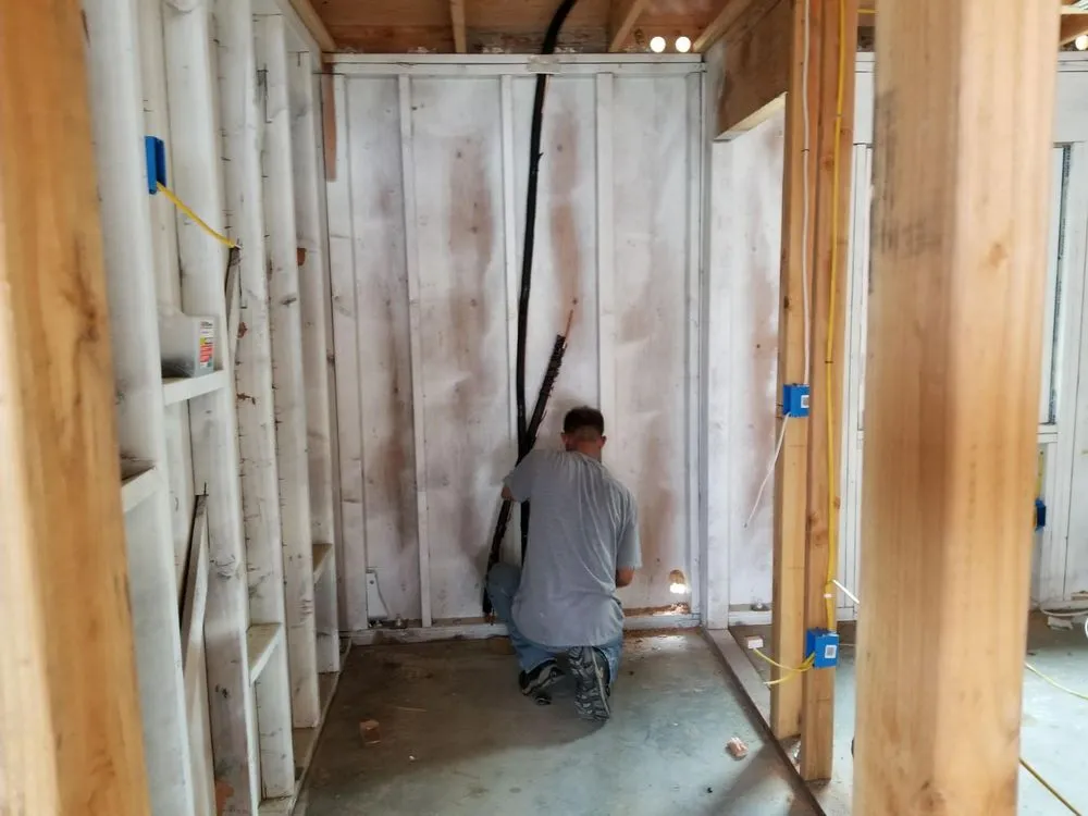 A technician from InsulationGuruInc.dbaHVACGuru in San Jose working on installing insulation and wiring inside a partially constructed room.